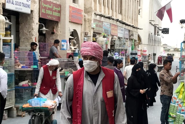 A man wears a protective face mask, following the outbreak of coronavirus, as he pushes a cart in souq Waqif in Doha, Qatar (photo credit: REUTERS)