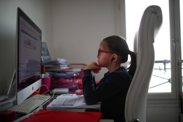 Anais, a student at the International Bilingual School (EIB), attends her online lessons in her bedroom in Paris as a lockdown is imposed to slow the rate of the coronavirus disease (COVID-19) spread in France, March 20, 2020. (photo credit: REUTERS/GONZALO FUENTES/FILE PHOTO)