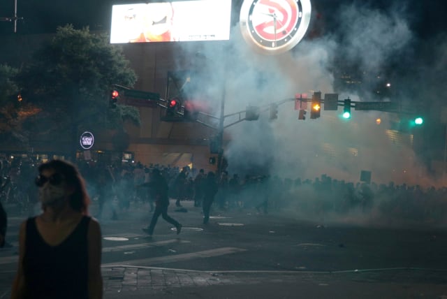 Protesters flee tear gas during a protest against the death in Minneapolis police custody of African-American man George Floyd, in Atlanta, Georgia, U.S. May 29, 2020.  (photo credit: REUTERS/DUSTIN CHAMBERS)
