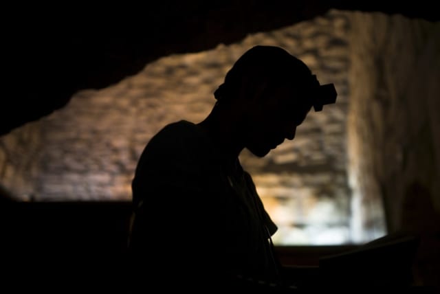 A Jewish worshipper prays next to the Western Wall on Tisha B'Av, a day of fasting and lament, in Jerusalem's Old City (photo credit: REUTERS/AMIR COHEN)