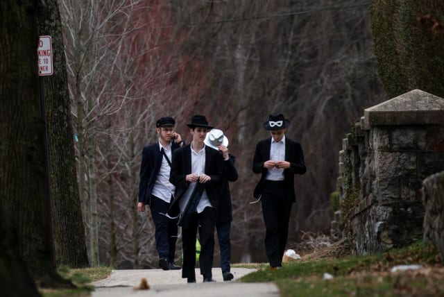 People walk on a street less than a mile away from Young Israel orthodox synagogue in New Rochelle, New York, U.S., March 10, 2020. (photo credit: EDUARDO MUNOZ / REUTERS)