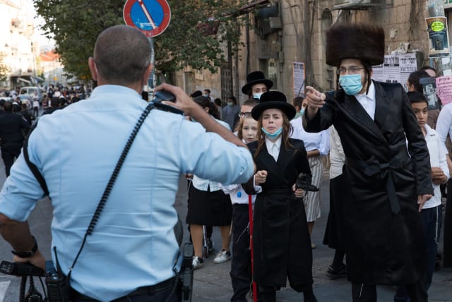 Israeli police officers clash with Ultra Orthodox Jewish men during a protest against the enforcement of coronavirus emergency regulations, in the Ultra Orthodox jewish neighborhood of Mea Shearim, Jerusalem, October 4, 2020 (photo credit: NATI SHOHAT/FLASH90)