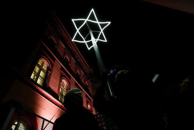 People take pictures of a light symbol, marking the place where Viennese synagogues once stood before they were destroyed, after a ceremony to mark the 80th anniversary of Kristallnacht, also known as Night of Broken Glass, in front of a then destroyed Synagogue in Vienna, Austria November 8, 2018. (photo credit: REUTERS)