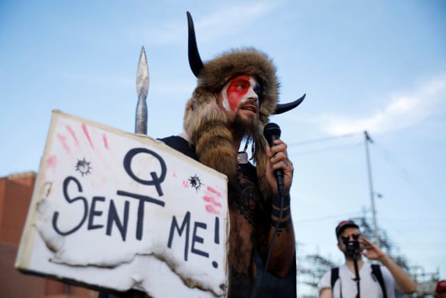 Jacob Chansley, also known as Jake Angeli, holding a sign referencing QAnon, speaks as supporters of U.S. President Donald Trump gather to protest about the early results of the 2020 presidential election (photo credit: CHENEY ORR/REUTERS)