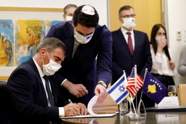 Israel's Foreign Minister Gabi Ashkenazi signs the agreement establishing diplomatic relations between Israel and Kosovo during a virtual ceremony with Kosovo's Foreign Minister Meliza Haradinaj Stublla, in the Israeli foreign ministry in Jerusalem February 1, 2021. (photo credit: AMIR COHEN/REUTERS)