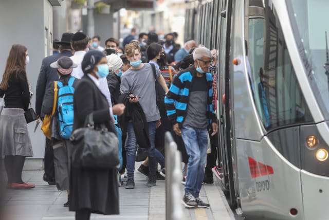 Israelis are seen boarding the light rail on Jaffa Street in Jerusalem after the coronavirus lockdown ends, on February 8, 2021. (photo credit: MARC ISRAEL SELLEM/THE JERUSALEM POST)