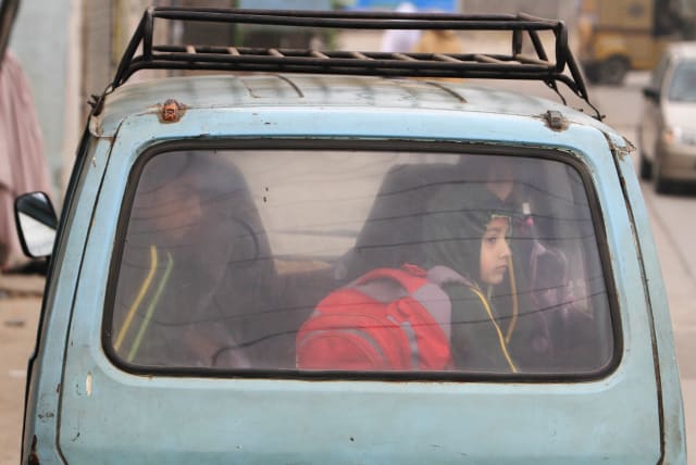 A boy sits in a van with others while heading to their school in Pakistan. (photo credit: FAISAL MAHMOOD/REUTERS)