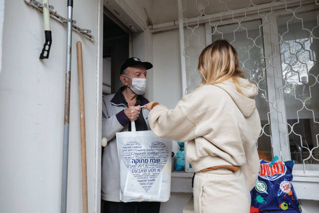 A VOLUNTEER delivers a food package to a Holocaust survivor in Ramat Gan in January. (photo credit: CHEN LEOPOLD/FLASH90)
