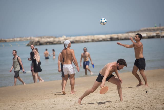 Israelis enjoy the beach on a hot spring day, in Tel Aviv, April 06, 2021 (photo credit: MIRIAM ALSTER/FLASH90)
