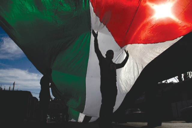 A MAN holds a Palestinian flag. One state is not an option. (photo credit: RAHIM KHATIB/FLASH90)