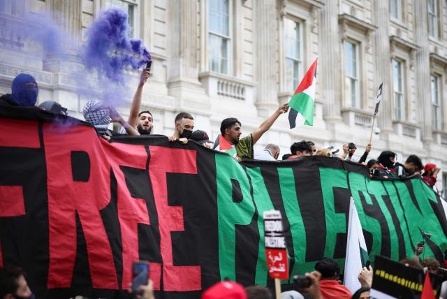 Pro-Palestine protesters hold a banner, as they demonstrate outside Downing Street in London, Britain, June 12, 2021. (photo credit: REUTERS/HENRY NICHOLLS)