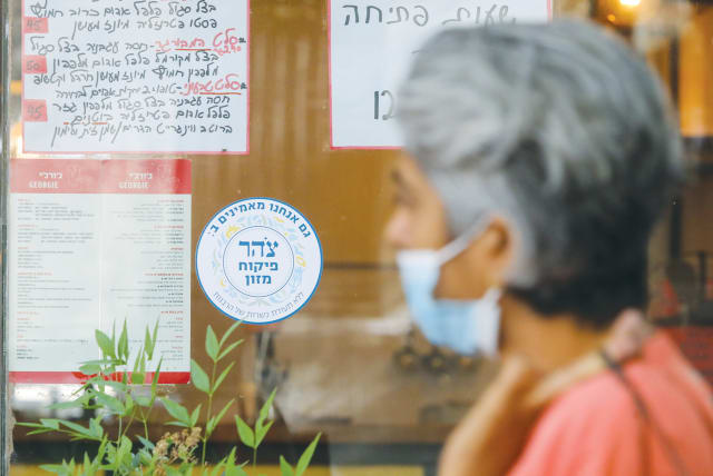  A WOMAN walks past a Jerusalem eatery with a Tzohar kashrut certificate. (photo credit: MARC ISRAEL SELLEM/THE JERUSALEM POST)