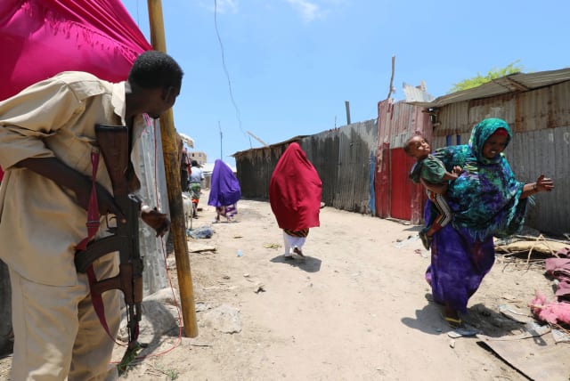 A Somali soldier holds position as civilians evacuate from the scene of a suicide explosion after al-Shabaab militia stormed a government building in Mogadishu, Somalia, March 23, 2019. (photo credit: REUTERS/FEISAL OMAR)