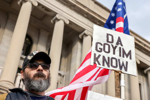  A protestor carries a white supremacist and antisemitic sign outside the Kenosha County Courthouse on the second day of jury deliberations in the Kyle Rittenhouse trial, in Kenosha, Wisconsin, US, November 17, 2021.  (photo credit: REUTERS/EVELYN HOCKSTEIN)
