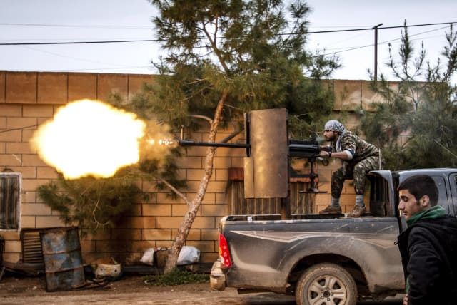A fighter of the Kurdish People's Protection Units (YPG) fires an anti-aircraft weapon from Tel Tawil village in the direction of Islamic State fighters positioned in the countryside of the town of Tel Tamr, February 25, 2015. (photo credit: REUTERS/RODI SAID)