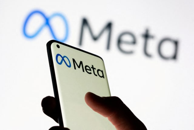  Woman holds smartphone with Meta logo in front of a displayed Facebook's new rebrand logo Meta in this illustration picture taken October 28, 2021.  (photo credit: REUTERS/DADO RUVIC/ILLUSTRATION)