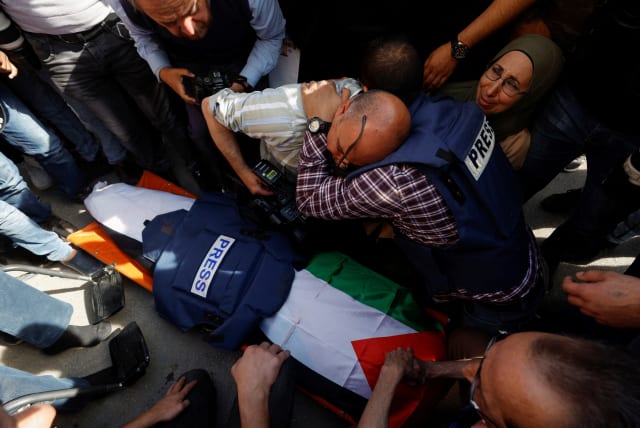 Journalists mourn next to the body of Al Jazeera reporter Shireen Abu Akleh, who was killed during IDF-Palestinian clashes in Jenin on May 11, 2022. (photo credit: REUTERS/MOHAMAD TOROKMAN)