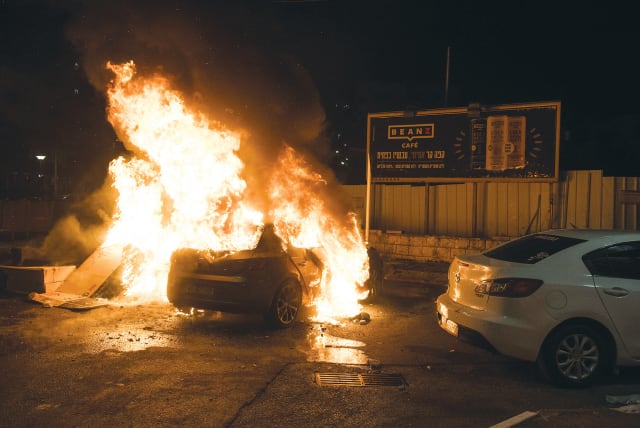  A CAR is set on fire in Acre, May 2021. Arab radicals are violent, dangerous and waiting to strike again at the Jews. (photo credit: RONI OFER/FLASH90)