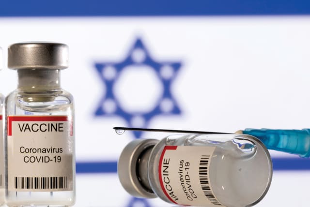  Vials containing the corona vaccine and a syringe are displayed in front of an Israeli flag. (photo credit: DADO RUVIC/REUTERS)