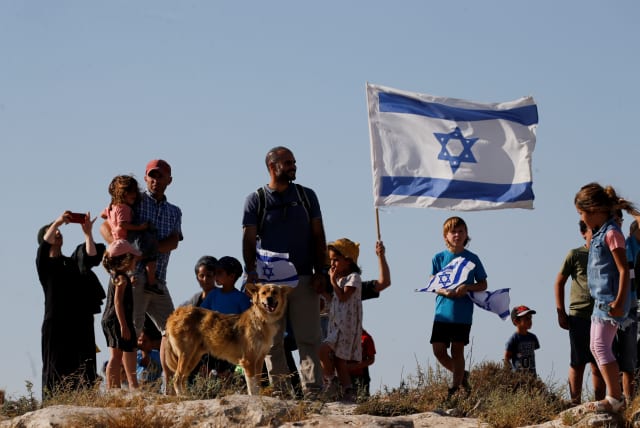  Jewish settlers look on during a march near Hebron in the West Bank, June 21, 2021 (photo credit: REUTERS/MUSSA QAWASMA)