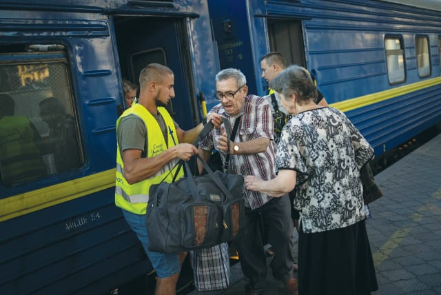  A VOLUNTEER helps a man as people arrive on a train from war-affected areas of eastern Ukraine, earlier this week.  (photo credit: Alkis Konstantinidis/Reuters)