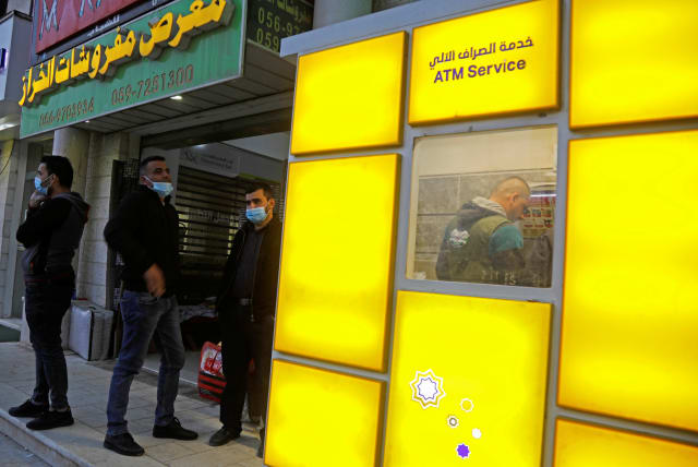  Palestinian Authority public servants wait to receive their salaries via an automated teller machine (ATM) outside a bank, in Tubas in the West Bank December 3, 2020.  (photo credit: REUTERS/RANEEN SAWAFTA)