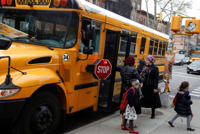 Orthodox Jewish children get off a Yeshiva school bus, as New York City Mayor Bill de Blasio declared a public health emergency in parts of Brooklyn in response to a measles outbreak, in the Williamsburg neighborhood of Brooklyn in New York City, US, April 9, 2019. (photo credit: REUTERS/SHANNON STAPLETON)