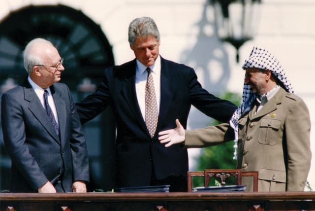  YASSER ARAFAT reaches to shake hands with Yitzhak Rabin, as Bill Clinton stands between them, after the signing of the Israel-PLO Declaration of Principles, at the White House on September 13, 1993. (photo credit: GARY HERSHORN/REUTERS)