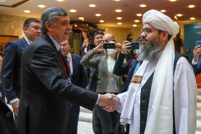  Russian presidential envoy to Afghanistan Zamir Kabulov shakes hands with a representative of the Taliban delegation Mawlawi Shahabuddin Dilawar before the beginning of international talks on Afghanistan in Moscow, Russia, October 20, 2021.  (photo credit: ALEXANDER ZEMLIANICHENKO/REUTERS)