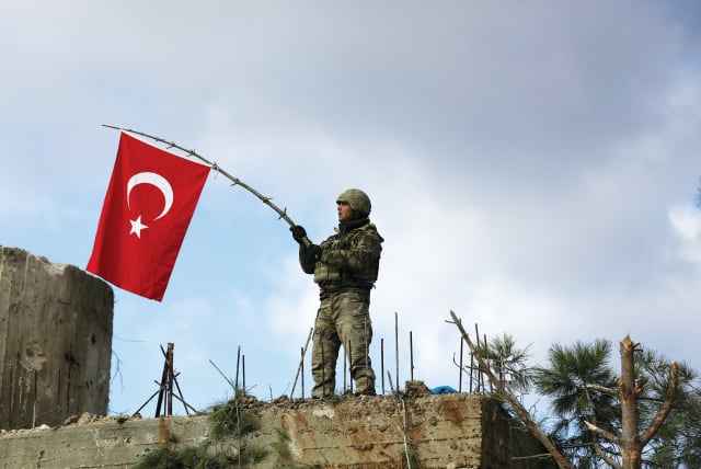  A TURKISH soldier waves a flag on Mount Barsaya, northeast of Afrin, Syria, in January 2018 (photo credit: Khalil Ashawi/Reuters)