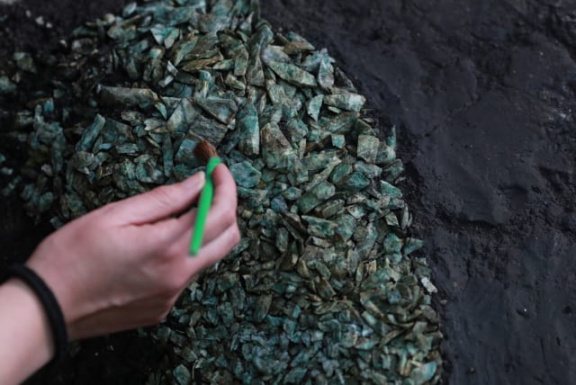  An archeologist cleans a ritual Aztec offering holding a large deposit of precious green stone fragments, the first of its kind ever found and likely from a lapidary workshop, discovered recently in circular pit just off the steps of the Templo Mayor, the Aztec empire’s most sacred temple (photo credit: REUTERS)