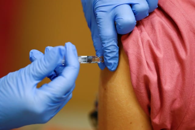  A member of the medical staff receives a flu vaccine at the department where patients suffering from the coronavirus disease (COVID-19) are treated in the Intensive Care Unit (ICU) at Havelhoehe community hospital in Berlin, Germany, October 30, 2020. (photo credit: REUTERS/FABRIZIO BENSCH)