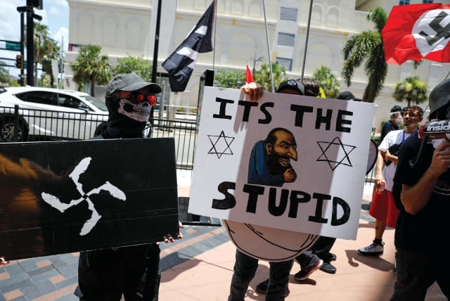  Demonstrators hold antisemitic symbols and signs as they protest outside the Tampa Convention Center, where Turning Point USA’s Student Action Summit was being held, in Tampa, Florida on July 23, 2022.  (photo credit: MARCO BELLO/REUTERS)