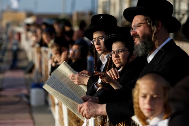 An ultra-Orthodox Jewish family takes part in the Tashlikh ritual, to symbolically cast away sins, ahead of Yom Kippur, the Jewish Day of Atonement, in Ashdod, Israel, October 3, 2022. (photo credit: REUTERS/AMIR COHEN)