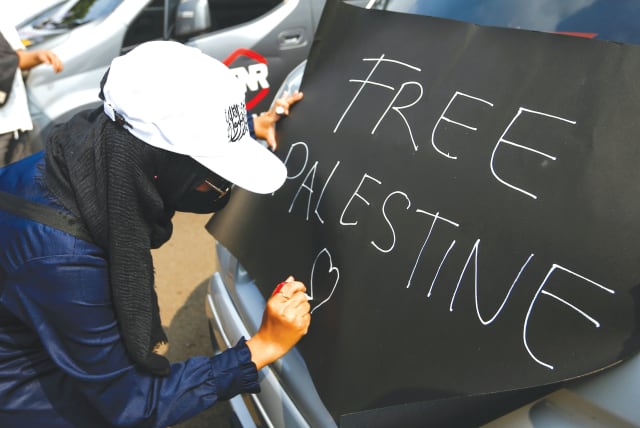 A PROTESTER writes a placard reading ‘Free Palestine,’ during a protest against Israel outside the US Embassy in Jakarta, last year. When people shout ‘Free Palestine,’ it is a call for genocide, another Holocaust, says the writer. (photo credit: AJENG DINAR ULFIANA/REUTERS)