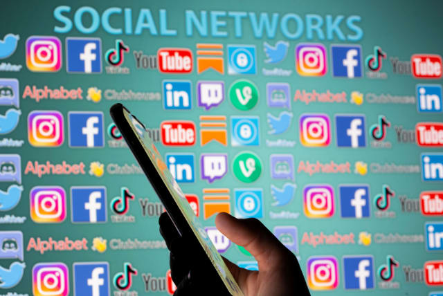 Woman with smartphone is seen in front of displayed social media logos in this illustration taken, May 25, 2021. (photo credit: REUTERS/DADO RUVIC/ILLUSTRATION)