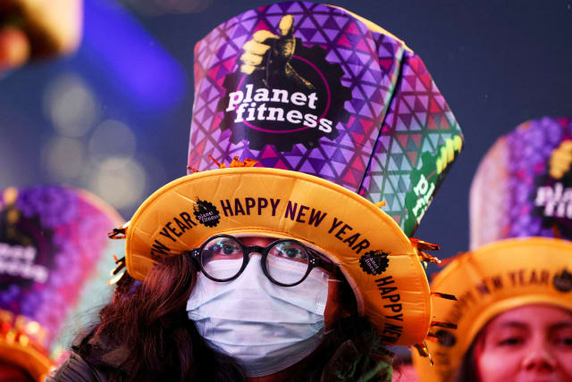  A person wearing a face mask is seen amongst revelers in Times Square during the first New Year's Eve event without restrictions since the coronavirus disease (COVID-19) pandemic in the Manhattan borough of New York City, New York, US, December 31, 2022. (photo credit: REUTERS/ANDREW KELLY)
