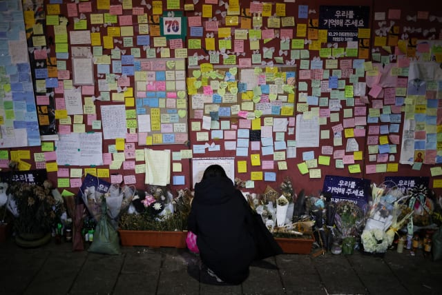  A woman reads condolences messages attached to the wall of a narrow alley of Itaewon where the deadly Halloween crush that killed more than 150 in October happened, in Seoul, South Korea, December 18, 2022. (photo credit: KIM HONG-JI/ REUTERS)