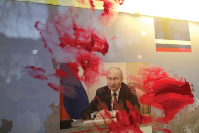  A PORTRAIT of Russian President Vladimir Putin is smeared with red paint during an anti-war protest outside the Russian Embassy in Bucharest, Romania, on February 26, 2022, days after the invasion of Ukraine. (photo credit: Inquam Photos/Octav Ganea/via Reuters)