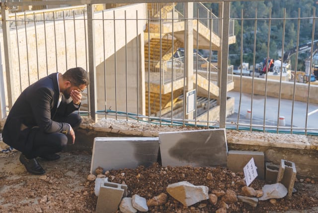  AFTER THE funeral, a mourner crouches at the grave of six-year-old Yaakov Israel Pally, killed in a car-ramming attack in Jerusalem, earlier this month. (photo credit: YONATAN SINDEL/FLASH90)
