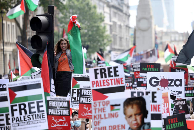 A protester climbs a traffic light pole during a pro-Palestine demonstration outside Downing Street in London, Britain, June 12, 2021. (photo credit: REUTERS/HENRY NICHOLLS)