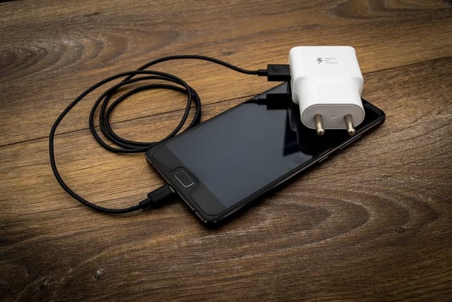  Illustrative image of a phone and charger. (photo credit: WALLPAPER FLARE)
