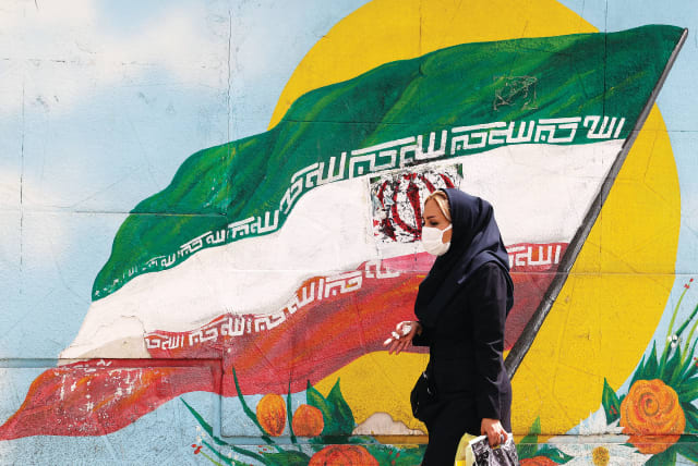  A WOMAN walks past an Iranian flag painted on a wall in a street in Tehran earlier this week. (photo credit: Atta Kenare/AFP via Getty Images)