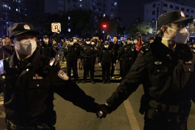  Police officers stand guard as people protest coronavirus disease (COVID-19) restrictions and hold a vigil to commemorate the victims of a fire in Urumqi, as outbreaks of the coronavirus disease continue, in Beijing, China, November 27, 2022. (photo credit: THOMAS PETER/REUTERS)