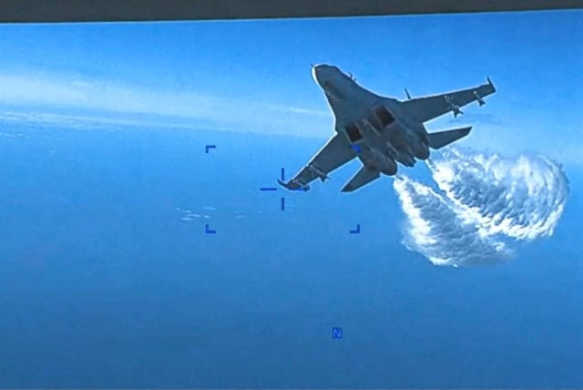 A Russian Su-27 military aircraft dumps fuel while flying by a US Air Force MQ-9 "Reaper" drone over the Black Sea, March 14, 2023 in this still image taken from handout video released by the Pentagon.  (photo credit: Courtesy of US European Command/The Pentagon/Handout via REUTERS)