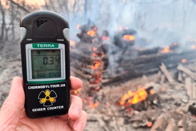  A geiger counter measures a radiation level at a site of fire burning in the exclusion zone around the Chernobyl nuclear power plant, outside the village of Rahivka, Ukraine April 5, 2020. Picture taken April 5, 2020. (photo credit: YAROSLAV YEMELIANENKO/REUTERS)