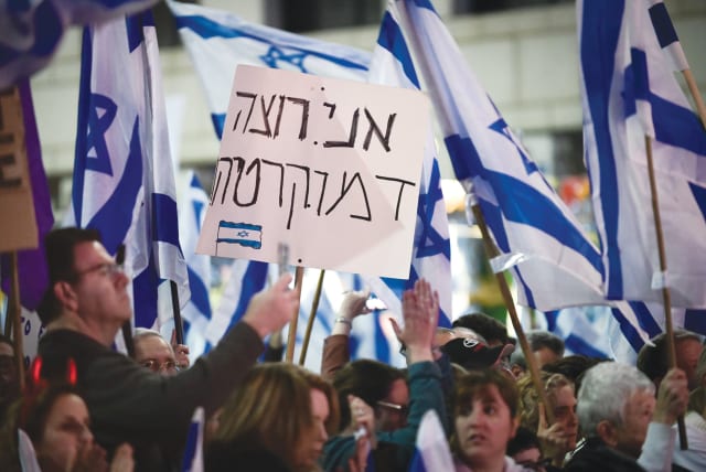  A PROTESTER holds a sign that reads: ‘I want democracy,’ at a demonstration in Herzliya, earlier this year.  (photo credit: AVSHALOM SASSONI/FLASH90)