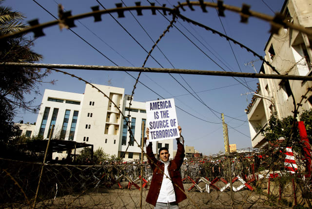  A Lebanese protester holds an anti-US banner behind razor wire during a protest in front of the US embassy near Beirut, March 15, 2005 (photo credit: REUTERS/DAMIR SAGOLJ/FILE PHOTO)