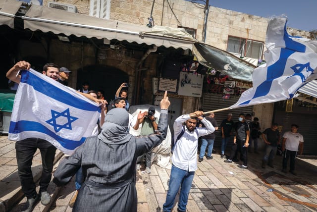  JEWISH MARCHERS wave the Israeli flag in front of an Arab woman in the Muslim Quarter of the Old City, on Jerusalem Day last year (photo credit: OLIVIER FITOUSSI/FLASH90)