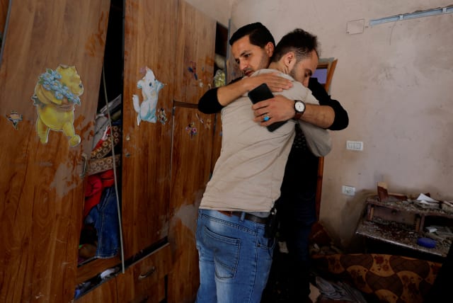 Palestinian man Mohammad Saed, whose fiancee Dania Adas was killed in a nearby Israeli strike that damaged her family's house, is consoled, inside her house in Gaza City May 10, 2023. (photo credit: MOHAMMED SALEM/REUTERS)